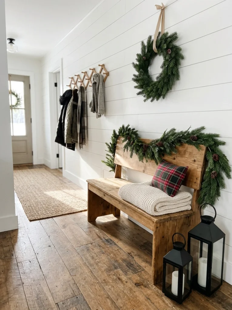 Farmhouse Christmas entryway decor with a rustic bench, plaid cushion, and evergreen accents.